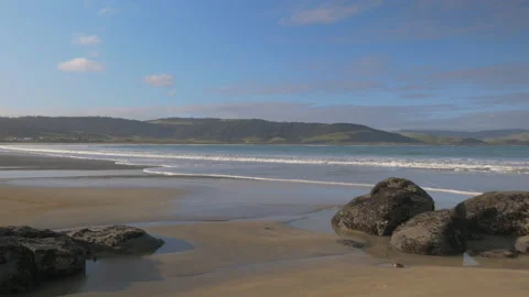 Travelling on a large sandy beach bordered by rocks, in New Zealand Stock Footage 219248546