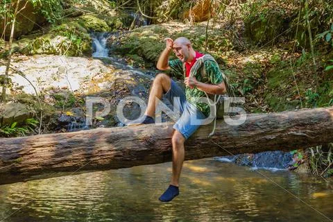 Travelling man sitting on a log near the river in the jungle Stock Photos