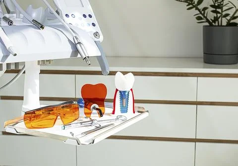 On the tray are various dental instruments, a model dental implant and bright Stock Photos