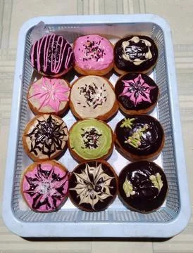 A tray of assorted donuts with different colors and designs Stock Photos