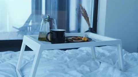 Tray with breakfast staying on the bed. Pancakes with fruits and tea, hotel room Stock Footage 254485294
