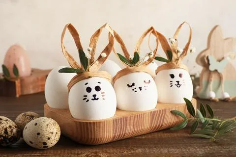 Tray with creative Easter eggs, leaves and flowers on brown wooden table near Stock Photos