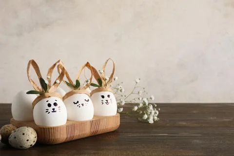 Tray with creative Easter eggs, leaves and flowers on brown wooden table near Stock Photos