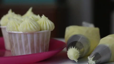 Tray with cupcakes with and without cream. Nearby are pastry bags of cream. C Stock Footage 140609087