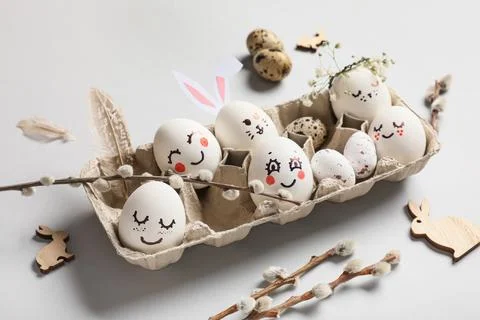Tray of cute painted Easter eggs with drawn face, flowers and pussy willow br Stock Photos