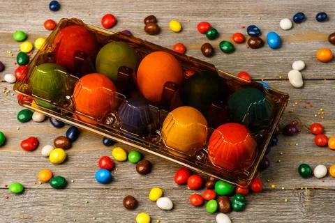 Tray with delicious colored Easter eggs and sweets on wooden bac Stock Photos