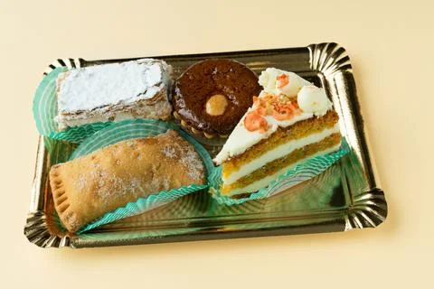 Tray with different cakes on a cream background. Small cakes Stock Photos