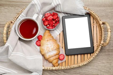 Tray with e-book reader and breakfast on wooden table, top view. Space for te Stock Photos