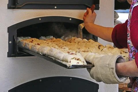 A tray of filled bread is pushed into the baking oven, outside wood stove on a Stock Photos