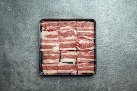 A tray of meat is on a grey surface Stock Photos