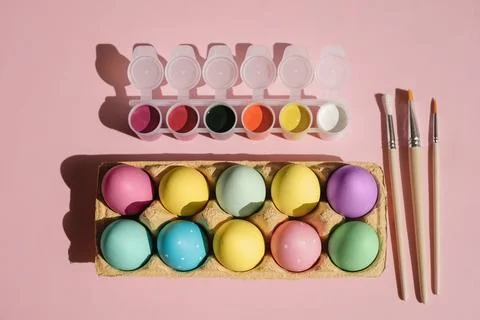 Tray with pastel-colored Easter eggs on a pink background Stock Photos
