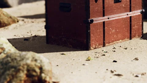 Treasure chest resting on sandy beach near rocks and sunlit shore Stock Footage 343533889
