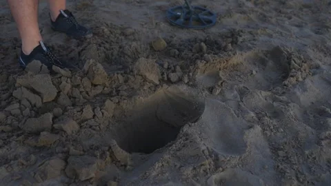 Treasure hunter digging a hole in the sand with a metal detector Video stock 347687612