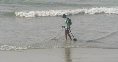 Treasure Hunter scanning the beach with a metal detector looking for valuables Stock Footage 234593752