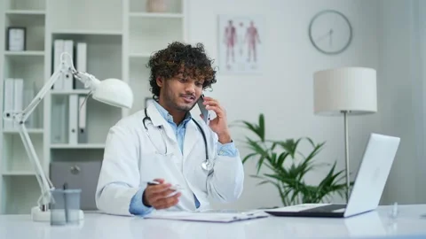 Treating doctor practitioner talking on phone with patient sitting in modern  Stock Footage 235479673