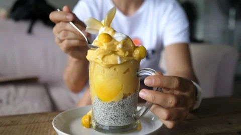 Treating yourself on vacations. A person scoops yellow vegan smoothie with a Video stock 154270467