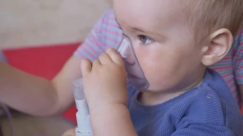 Treatment of lung disease with an inhaler. A little boy in the mask of an Stock Footage