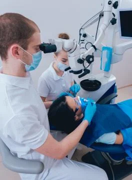 Treatment of root canals under a microscope, work with an assistant. Stock Photos