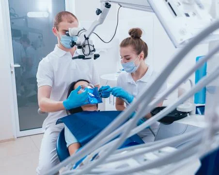 Treatment of root canals under a microscope, work with an assistant. Stock Photos