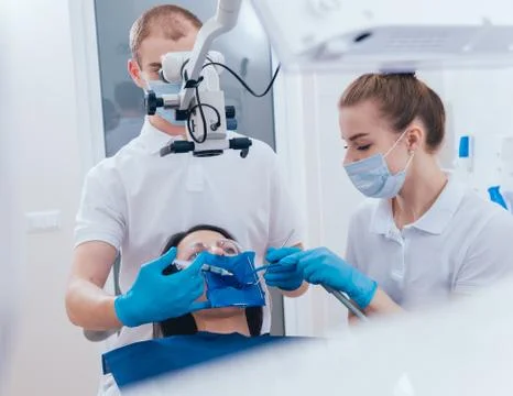 Treatment of root canals under a microscope, work with an assistant. Stock Photos