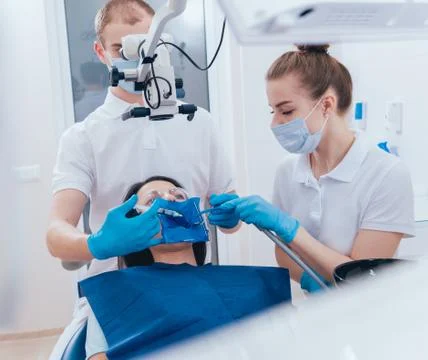 Treatment of root canals under a microscope, work with an assistant. Stock Photos