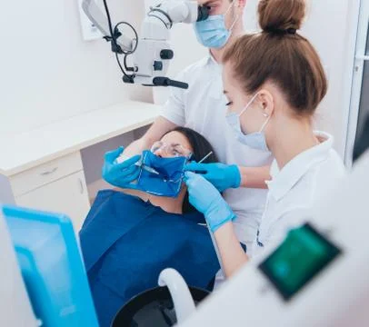 Treatment of root canals under a microscope, work with an assistant. Stock Photos