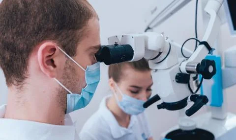 Treatment of root canals under a microscope, work with an assistant. Stock Photos