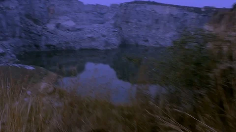 Trecking night evening up a cliff overlooking a lake 库存影片 100642960