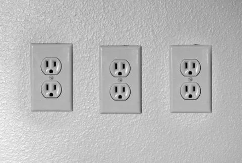 Tree american plug electric outlets on a plain neutral black and white wall Stock Photos