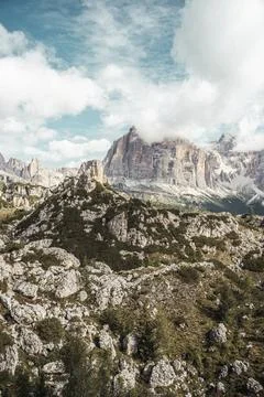 A tree and rockcovered mountain beneath a cloudy sky Stock Photos