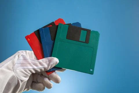 Tree blank floppy disc of multicolor in hand, on a blue background. Outdated  Stock Photos