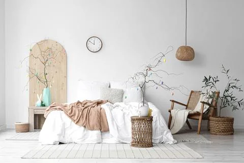 Tree branches decorated with Easter eggs on tables and comfortable bed in bed Stock Photos