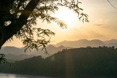 Tree branches framing sunset over mekong river luang prabang laos Stock Photos