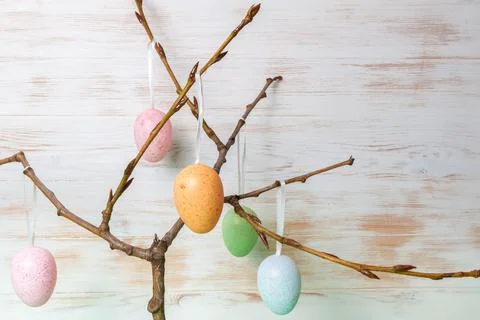 Tree branches with gentle colored Easter eggs on white painted vintage wooden Stock Photos
