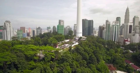 Tree-Covered Hill In Downtown Kuala Lumpur, Malaysia, Ascending Aerial Shot Stock Footage 79840465