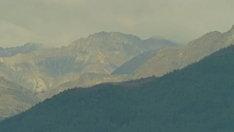 Tree covered hillside with rocky mountains behind Stock Footage 159752274
