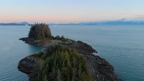 Tree-covered island in evening with mountains in the background Stock Footage 100618117
