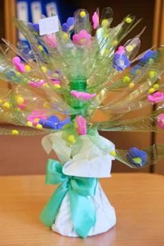 Tree crafted from recycled plastic bottles adorned with colorful flowers Stock Photos