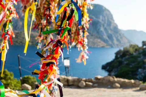 Tree in festive colored ribbons on the background of the sea and mountains. Stock Photos