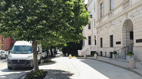 Tree-lined sidewalk beside white stone building Stock Footage 323712188