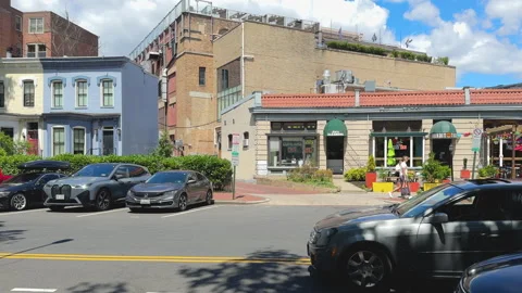 Tree-lined sidewalk in front of red building on busy street Stock Footage 323968289