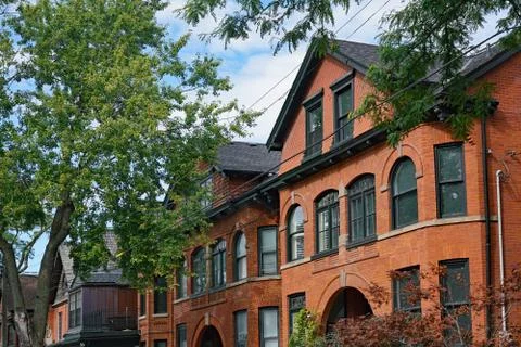 Tree lined street with large old brick houses with gables Stock Photos