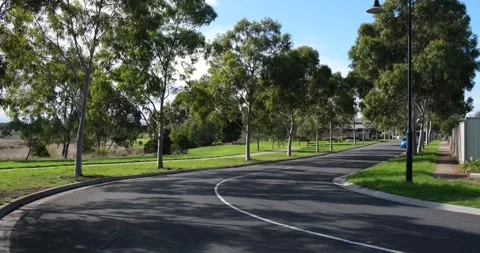 A tree-lined suburban road in a quiet residential neighbourhood of Melbourne Stock Footage 241153393