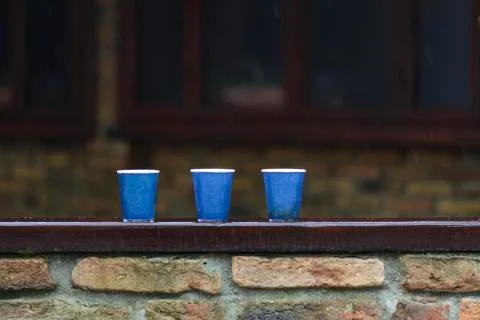 Tree paper cups on a bar, under the rain against blurry background. Stock Photos