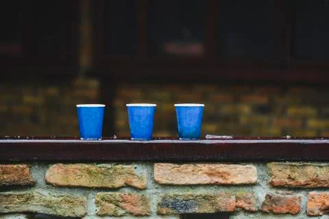 Tree paper cups on a bar, under the rain against blurry background. Stock Photos