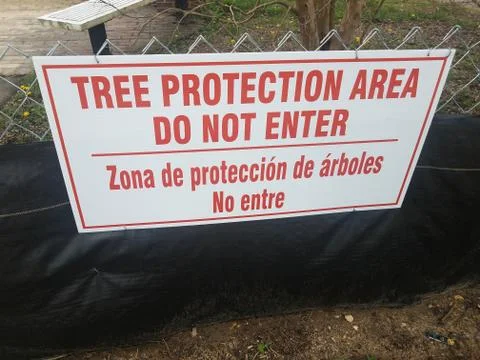 Tree protection area do not enter sign with spanish on fence Stock Photos