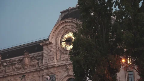 Tree reveal shot of Musee d Orsay illuminated clock at dusk in Paris, 4K Vídeos de archivo 344975424