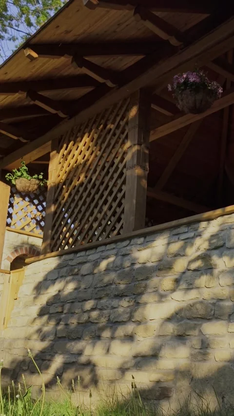 Tree shadows dancing on a rustic stone wall and a wooden terrace Stock Footage 334789763