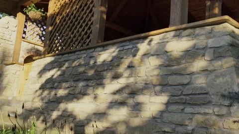 Tree shadows dancing on a rustic stone wall and a wooden terrace Stock-Footage 334789776