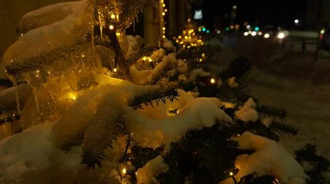 The tree of a small Christmas tree in icicles is illuminated with garlands near  Foto stock